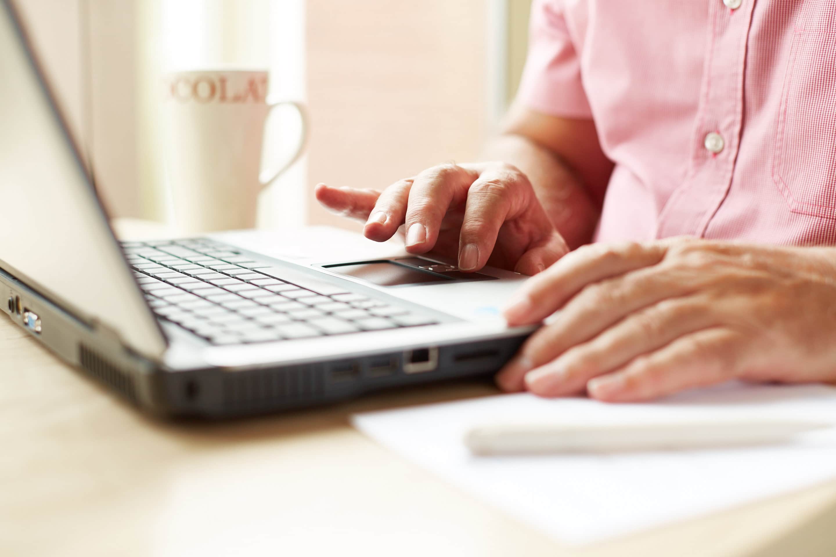 A person typing on a laptop zoomed in on hands.
