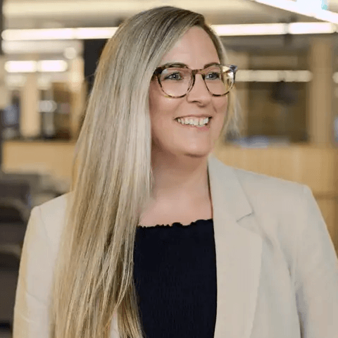 Image of female Cancer Research UK employee, standing and smiling in an office.
