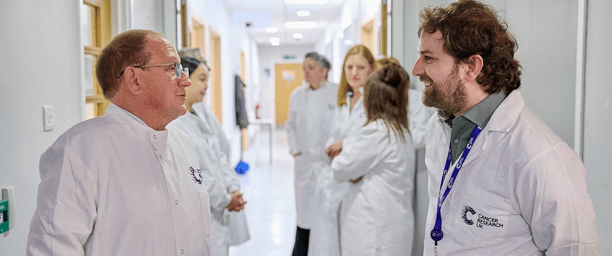 Several people stood in a hallway wearing labcoats.