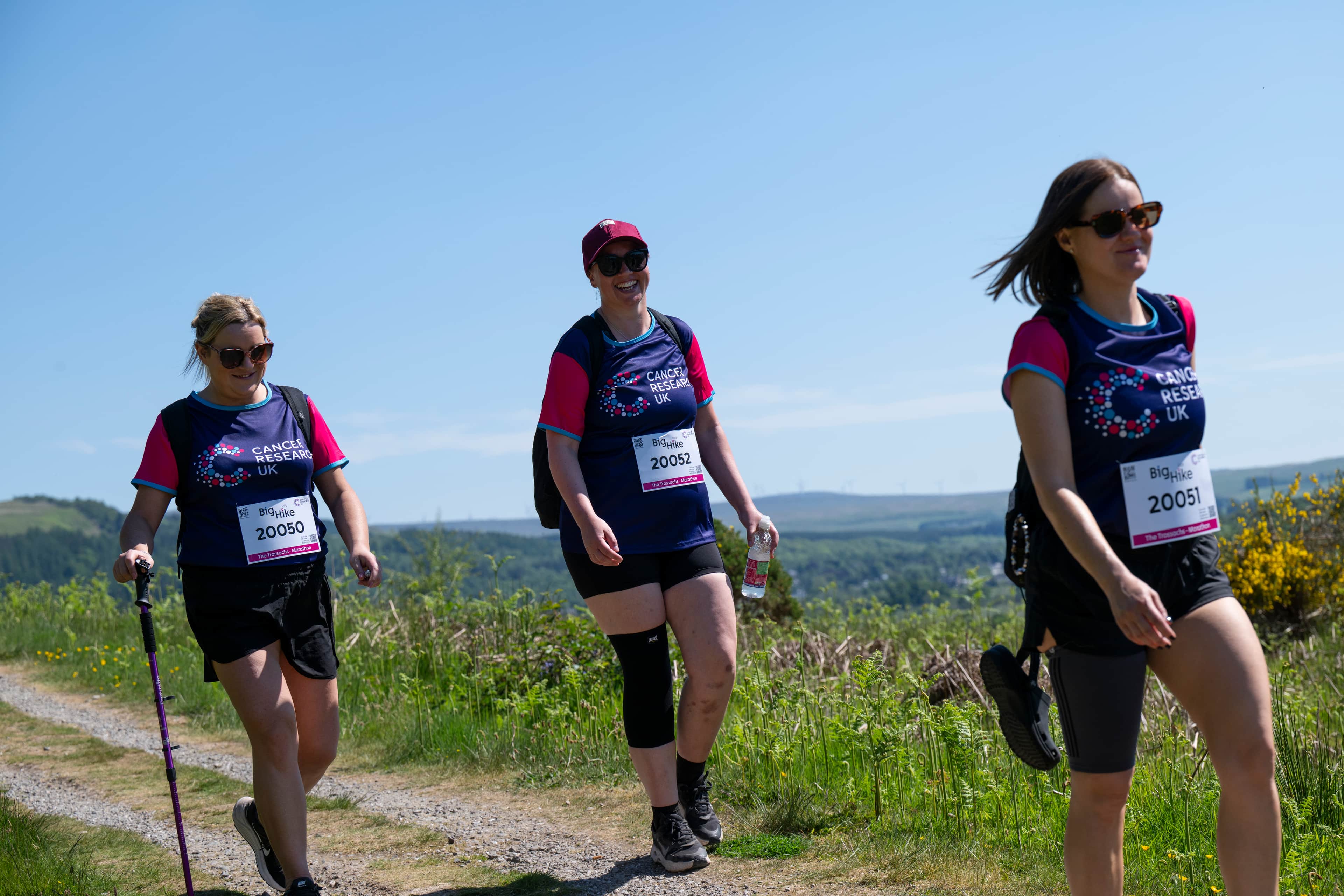 Three hikers walking along the countryside.