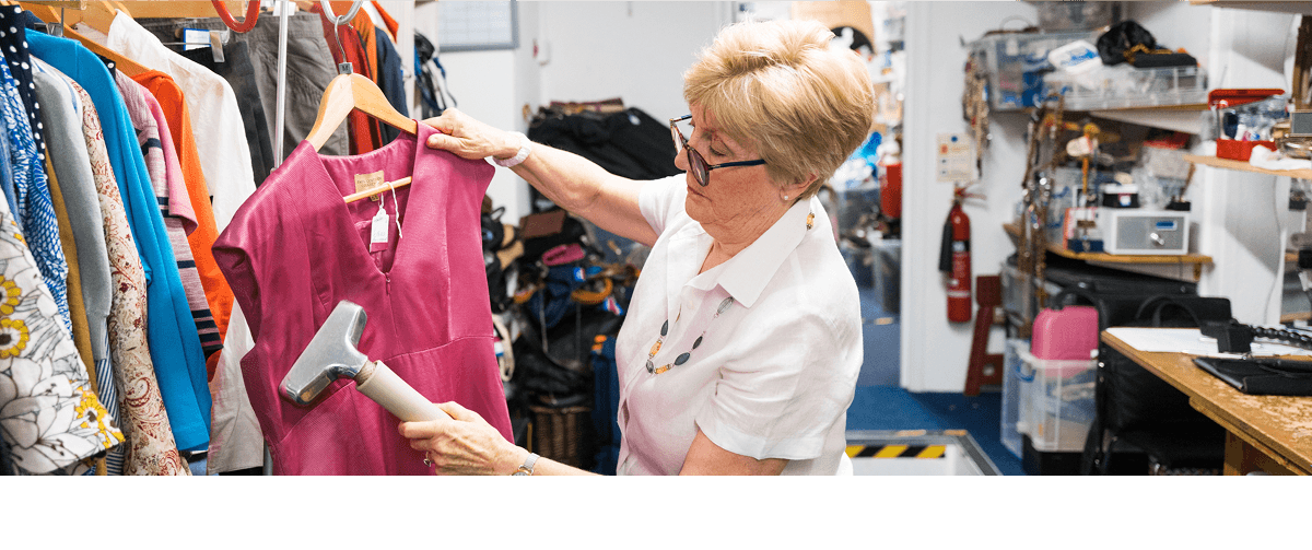 A photo of a Cancer Research UK shop volunteer steaming a shirt.