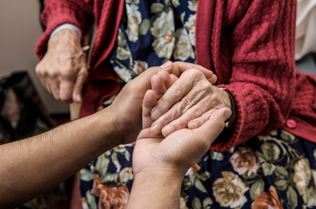 Photo of nurse holding patient hand.