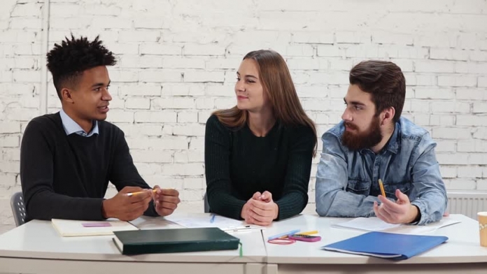 Three students sitting at a tablr