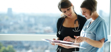 Female doctor and nurse in discussion over paperwork