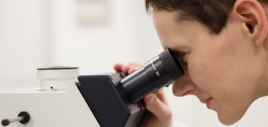 A female scientist looking down a microscope