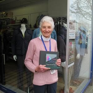Elizabeth holding a Flame of Hope trophy in front of a shop