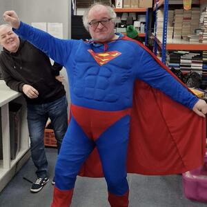 Paul wearing a Superman outfit and doing a typical Superman pose