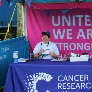 Rhona sitting behind a table at a Cancer Research UK event