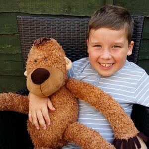 Rhys smiling and holding a teddy