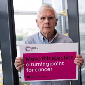 Philip holding a sign that reads 'Make this election a turning point for cancer'