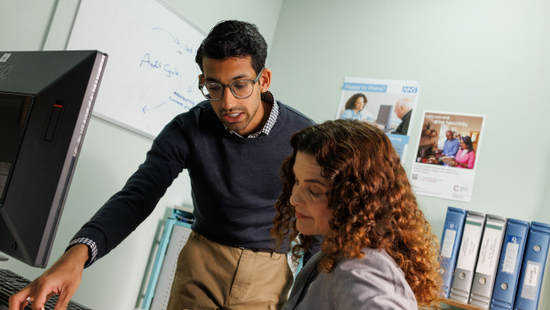 Two NHS doctors reviewing a patient's case file. Two NHS doctors reviewing a patient's case file.