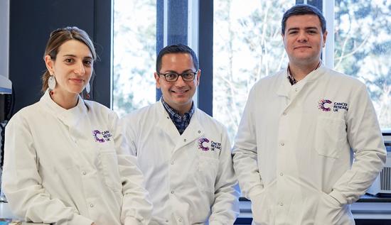 Three smiling researchers in a lab facing the camera
