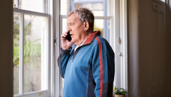 Man looking out a window on a phone call