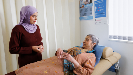 Patient is lay down discussing her symptoms with the doctor