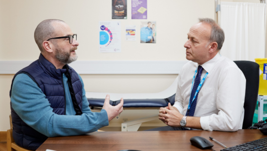 A patient having a conversation with a GP about possible cancer symptoms.