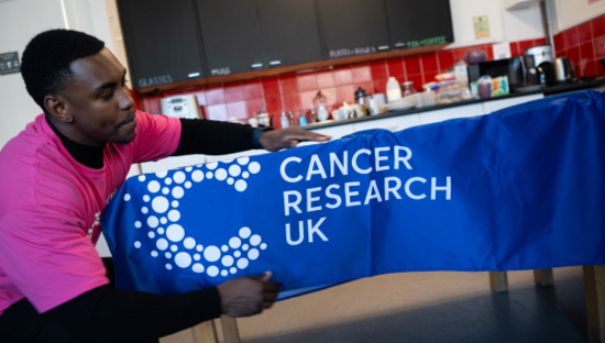 Man putting a CRUK branded table cover on. Photography: Laura Ashman