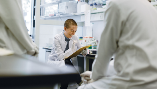 A scientist is holding a clipboard and writes down some data.