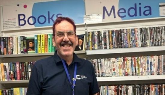 Terry smiling in front of the media section of the shop