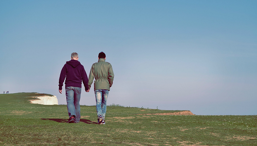 a couple walking along the top of a cliff
