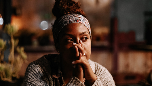 Women sitting at a table holding her head in her hands