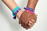 Friends holding hands wearing World Cancer Day unity bands