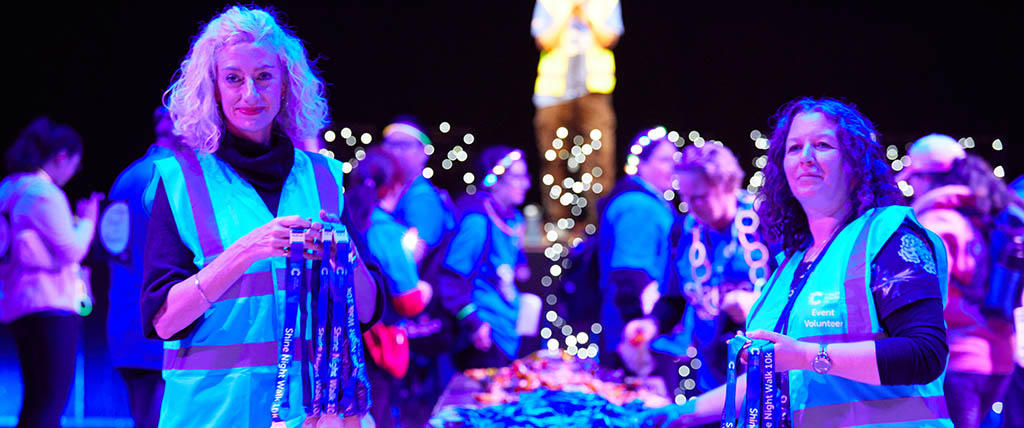 Shine Night walk volunteers giving out medals