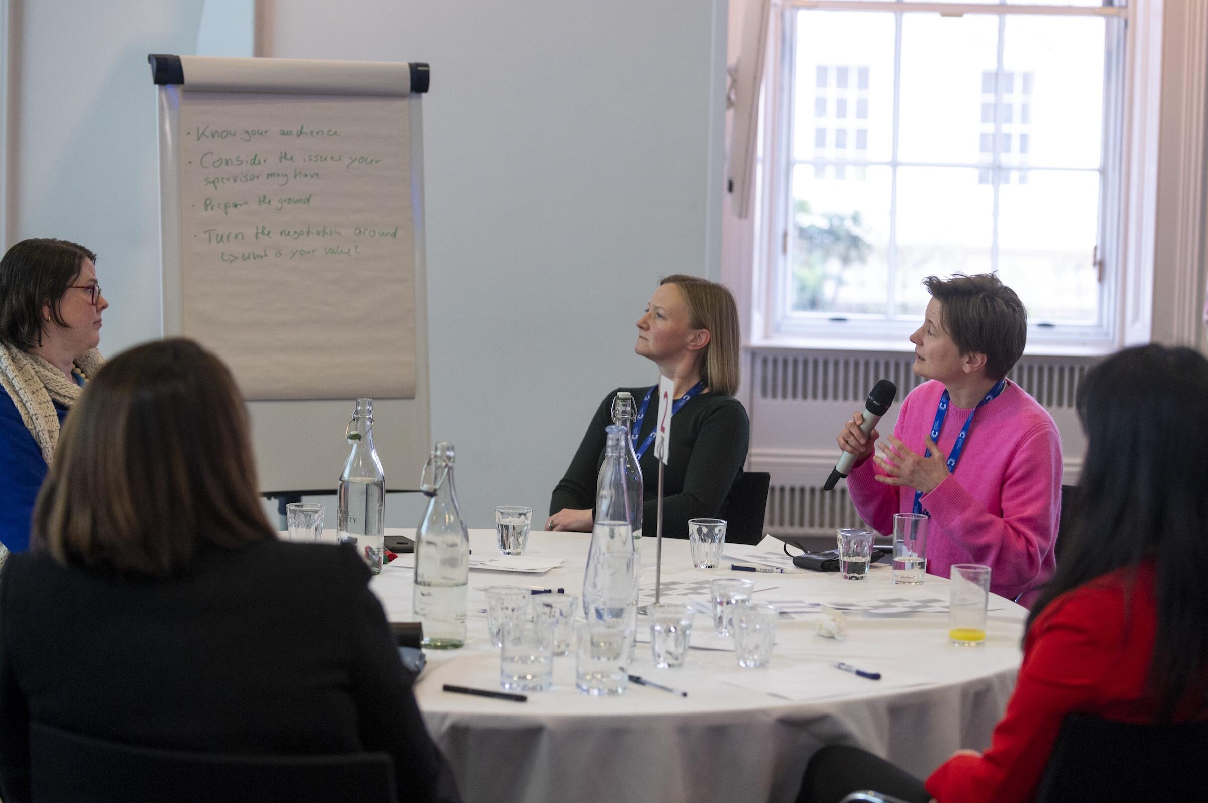 Five people around a round table having a discussion