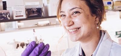 Researcher smiling and showing lab vial to the camera
