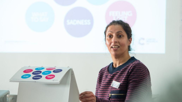 Talk Cancer session. Woman talking to group in front of a white board