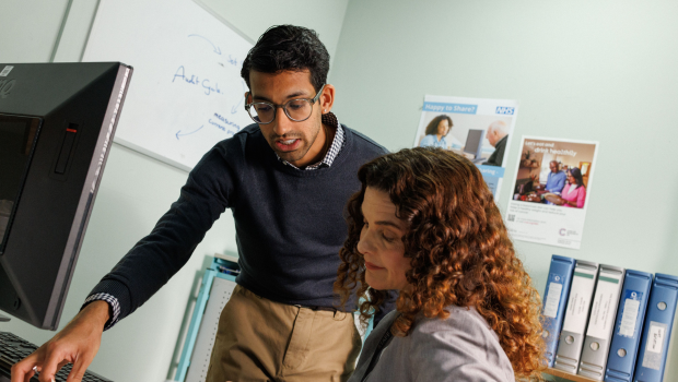 Two NHS doctors reviewing a patient's case file.