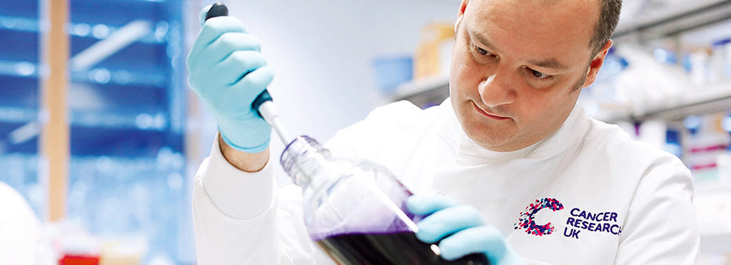 A Cancer Research scientist injects liquid into a flask