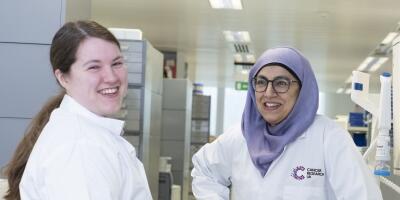 Two researchers stood in a lab talking to each other and smiling