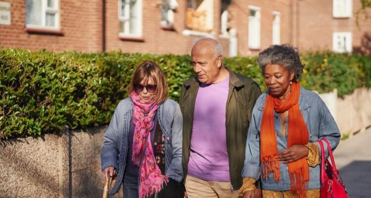 Three people walking down the street chatting to each other.