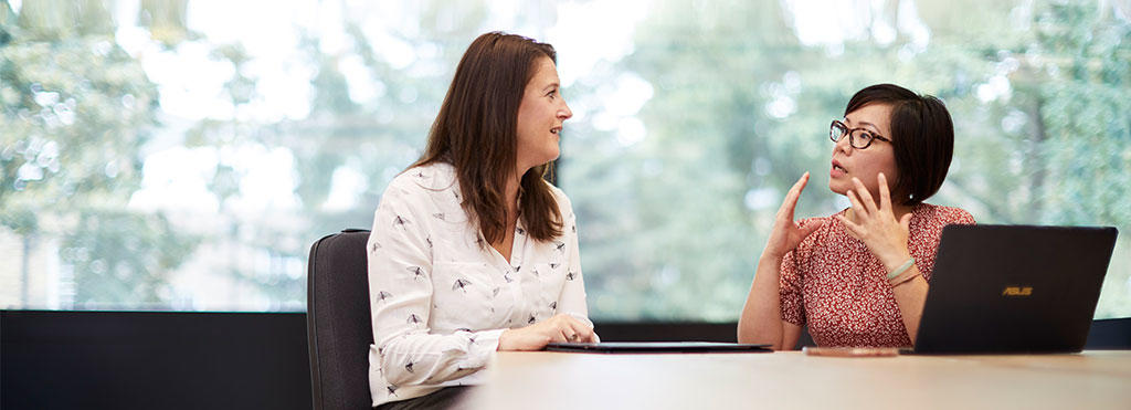 A photo of two people having a conversion in an office