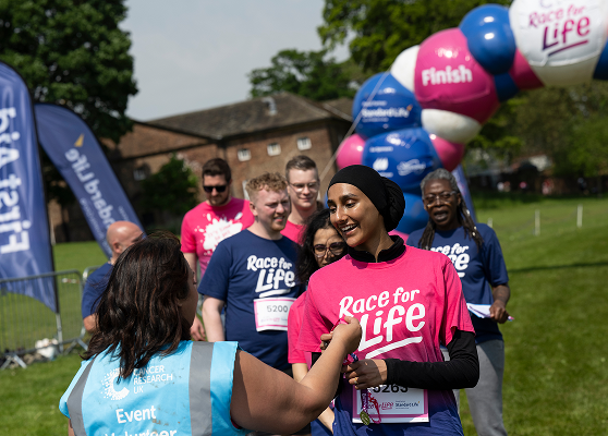 Volunteer giving a medal to a Race for Life runner