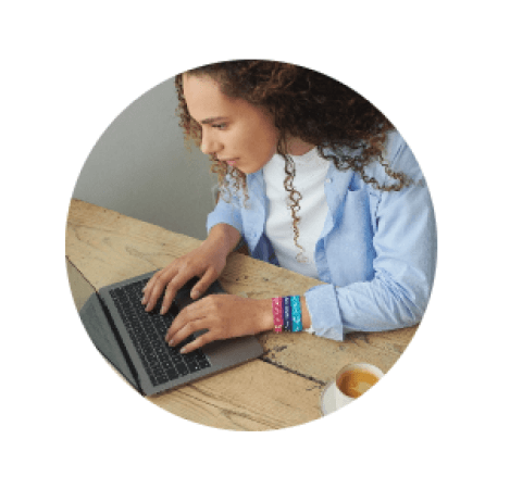 A woman with curly hair sat at her computer donating to Cancer Research UK