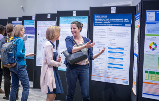 Two people discuss information boards at a conference