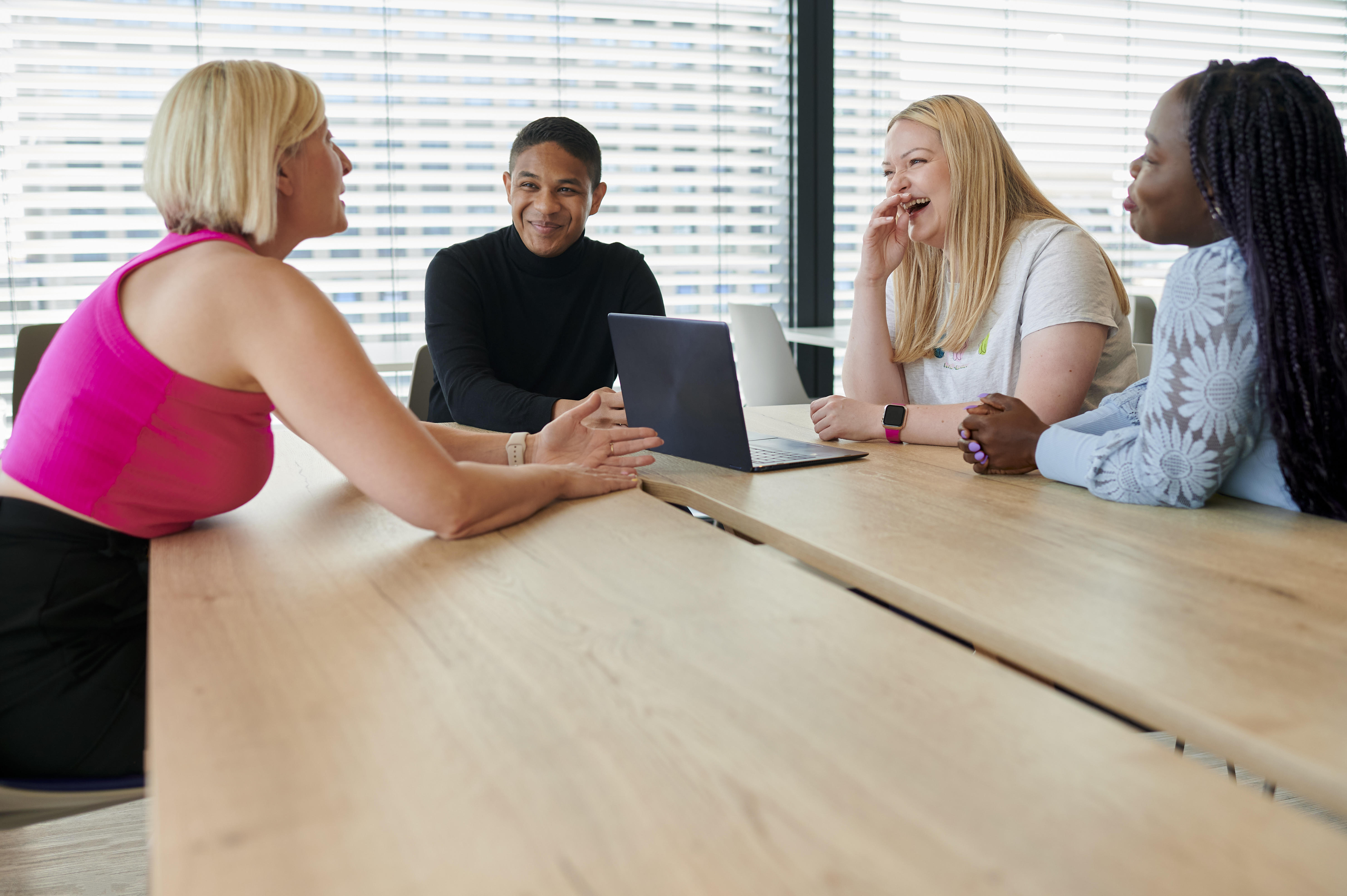 A white man with a hearing aid, a black woman and a black man talking in the office