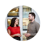 A photo of two people talking in an office