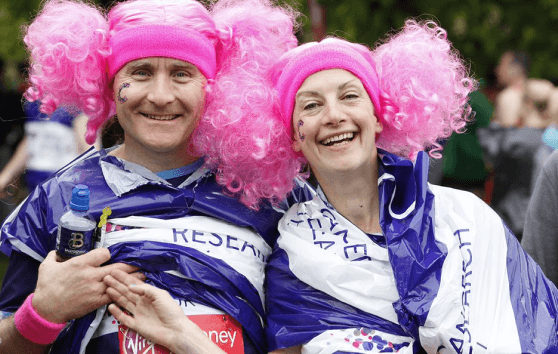 A man and a woman in pink wigs smiling fundraising for CRUK