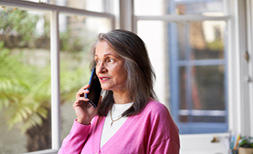 An older woman is at home and using the Cancer Research UK free will service over the phone to speak with a solicitor 