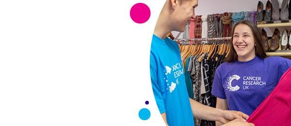 Girl in a purple t shirt laughing as she sorts clothes in a shop
