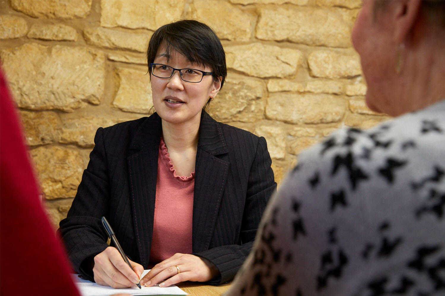 Solicitor writing on a piece of paper sitting opposite a couple