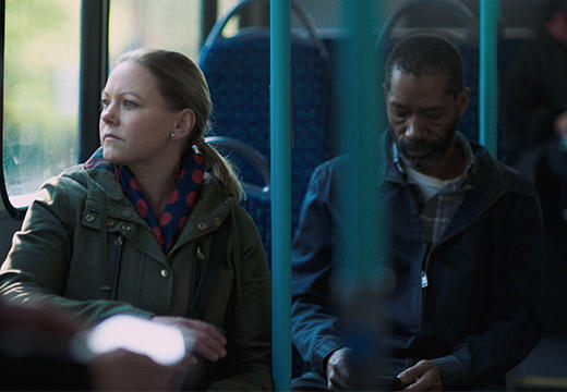 Two people sit on a bus as one looks out the window
