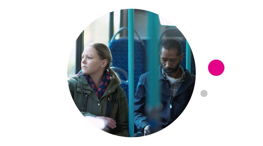 Two people seated, riding a bus