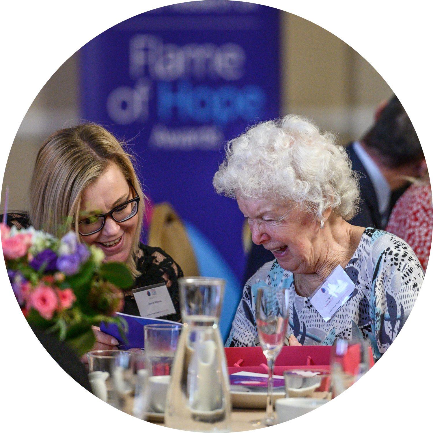 Katie and guest sitting at a table at the Flame of Hope Awards