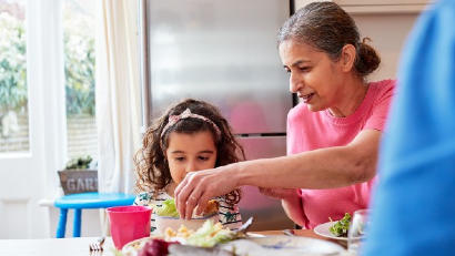 Grandmother giving salad to grandchild