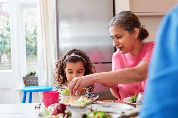 Grandmother giving salad to grandchild