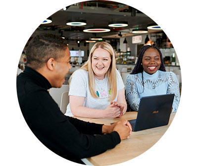 Three people sitting down and conversing and smiling in the office