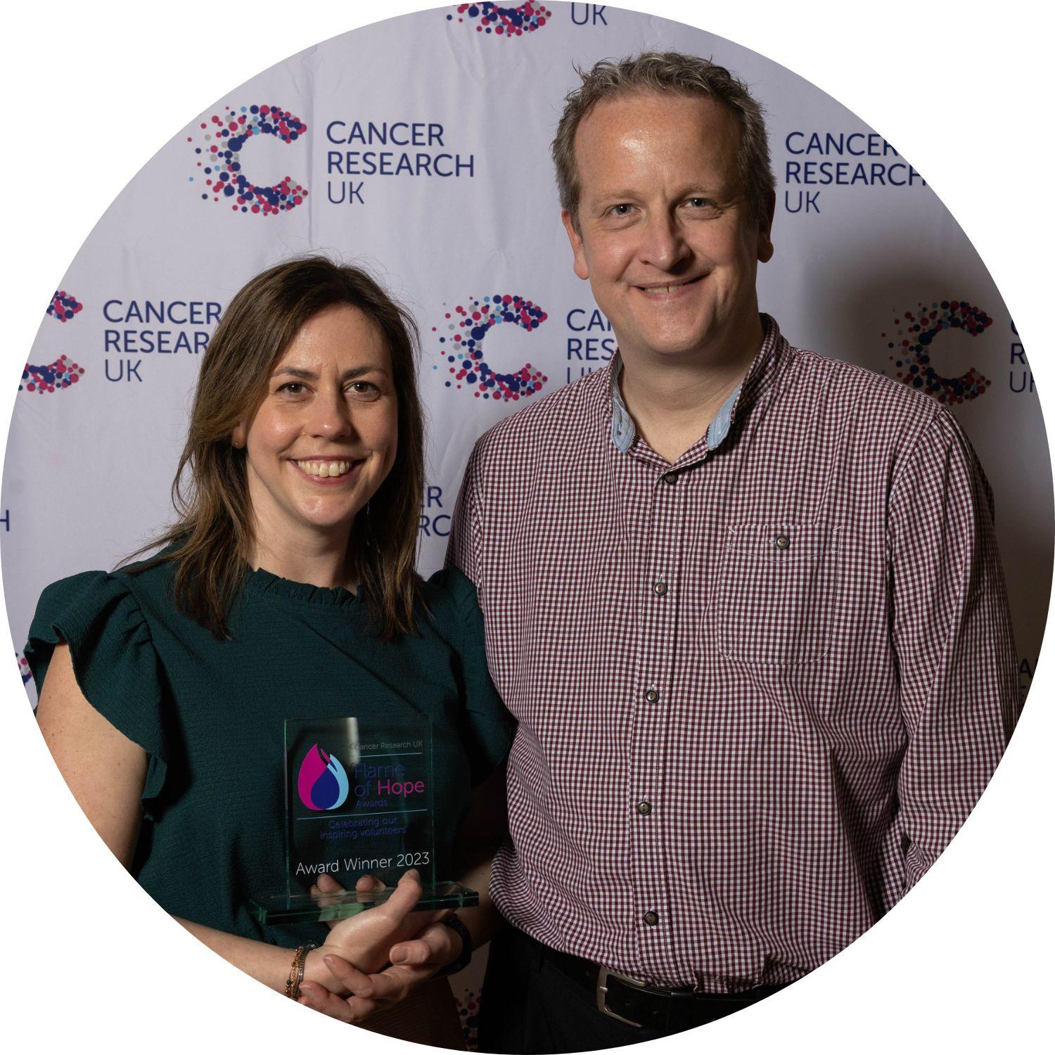 Laura holding a Flame of Hope trophy, with her guest to our right